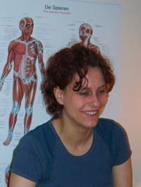 Astrid Engels, glimlachend voor een anatomische plaat van de spieren